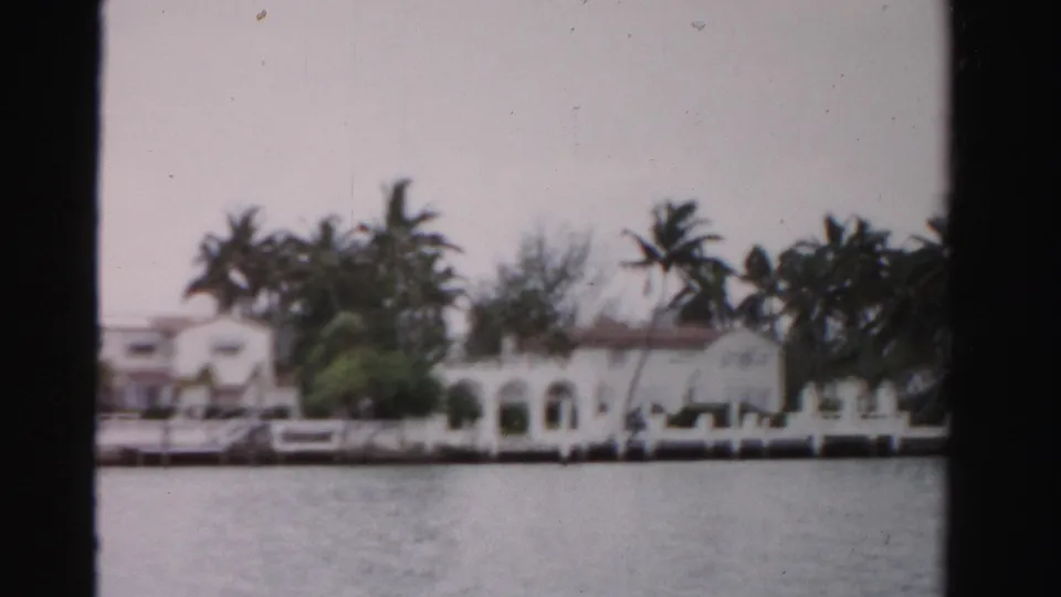 1955 Dade County waterfront homes with arched stucco features, palms, dockside edges, and water in the foreground.