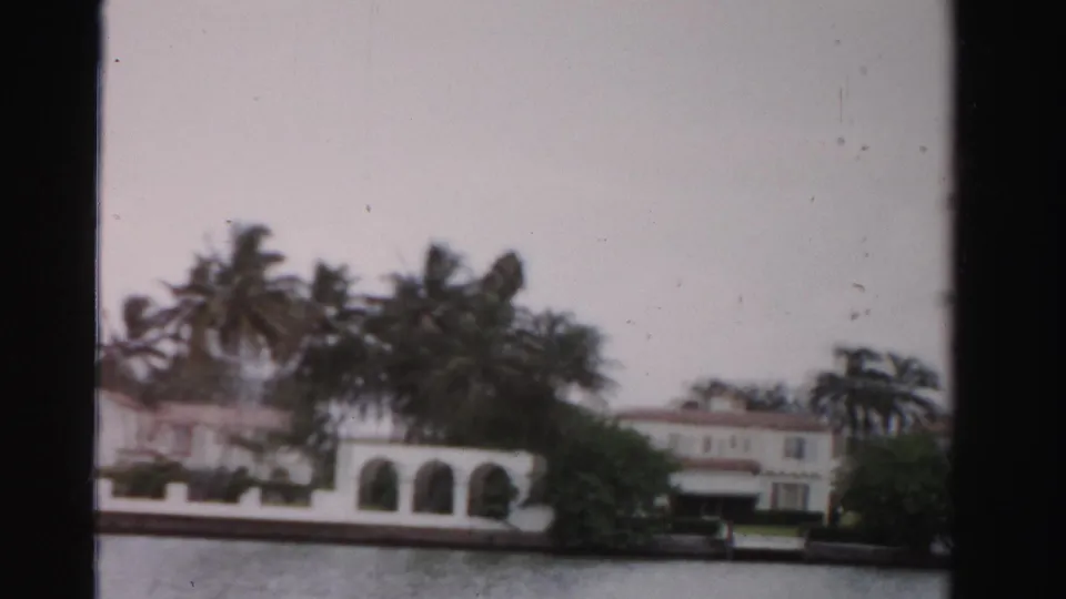 End of the 1955 Dade County pan showing arched waterfront architecture, palms, and a light-colored house beyond hedges.
