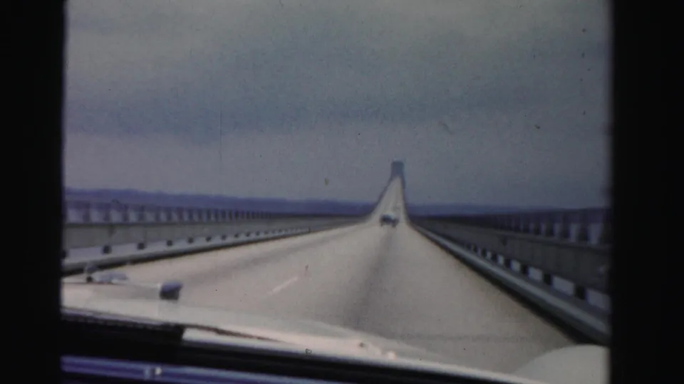 1955 Dade County road-trip footage shows an open stretch of bridge from inside a moving car, with water and distant shoreline visible.