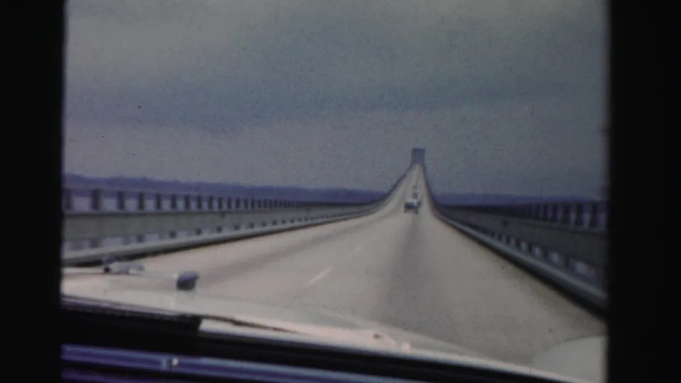 1955 Florida car-window perspective along a Dade County causeway, with guardrails and water visible beside the roadway.