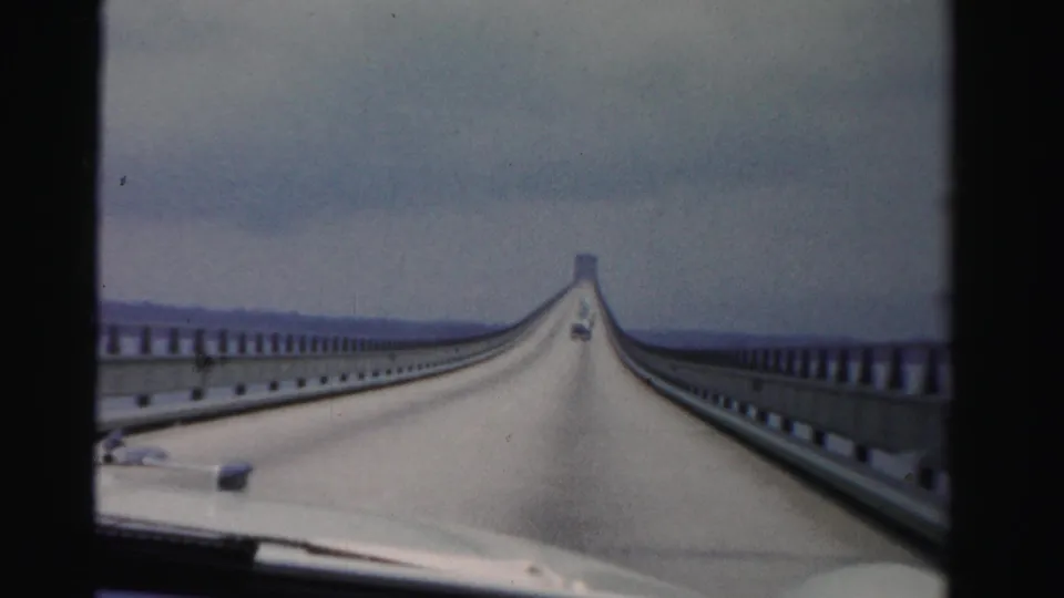 Dade County, Florida 1955 home-movie frame showing a car following another vehicle across a long causeway.