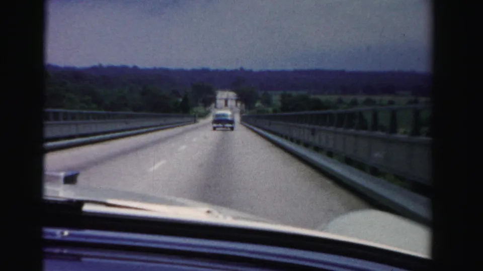 Dade County, Florida 1955 home-movie view from inside a car following another vehicle across a broad bridge.