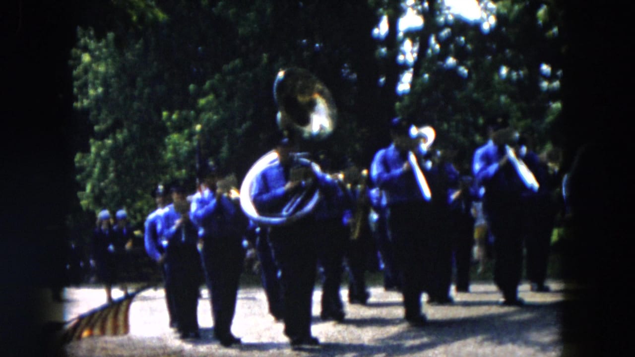 Marching band in blue uniforms approaches with a large tuba in front.