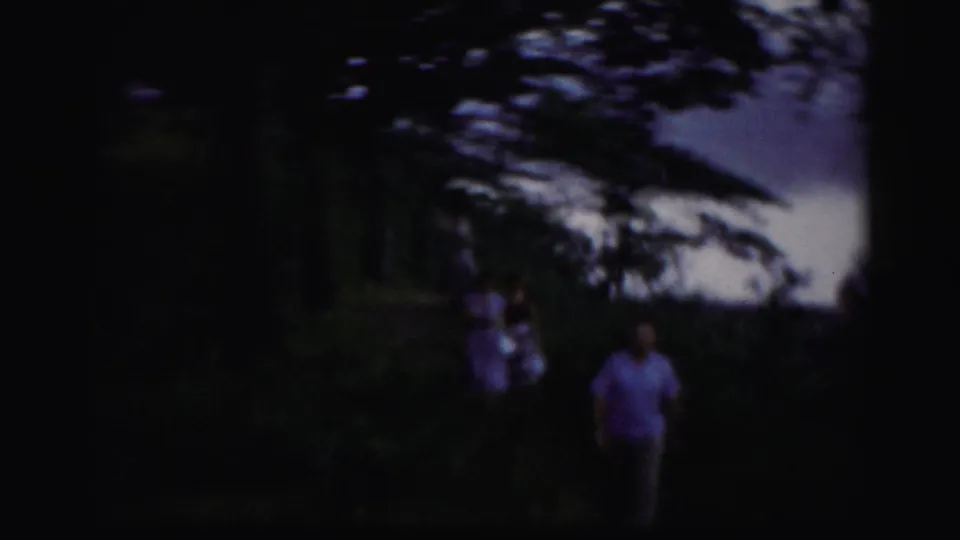 Several people walk toward the camera on a shaded riverside trail in archival 8mm footage from the Albany area.
