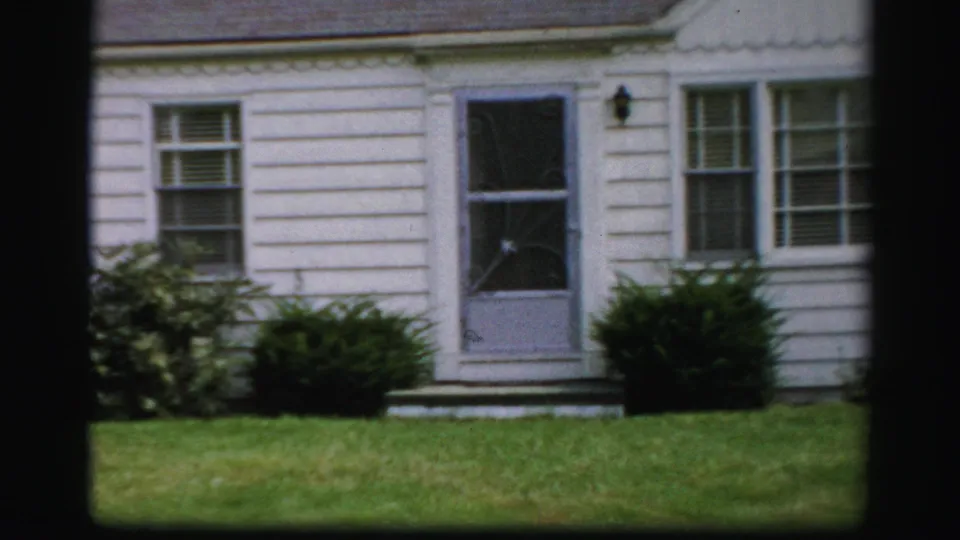 1950s Albany home exterior with a screen door, white clapboard siding, front windows, shrubs, and green lawn.