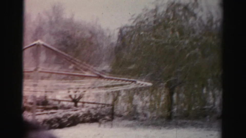Albany winter yard view on 8mm film, showing a snow-covered clothesline, bare trees, and soft faded color.