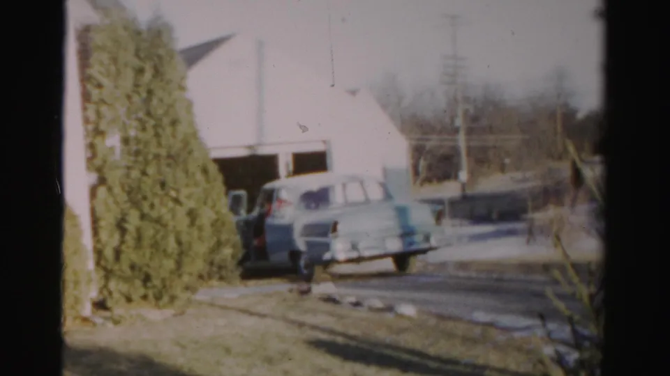 The light blue vintage car appears to reverse from the garage area along a residential driveway in Albany.
