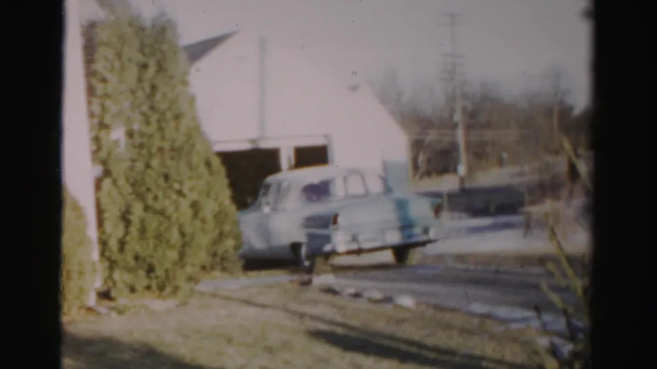 The car is farther from the garage, backing toward the road in a 1950s Albany residential scene.