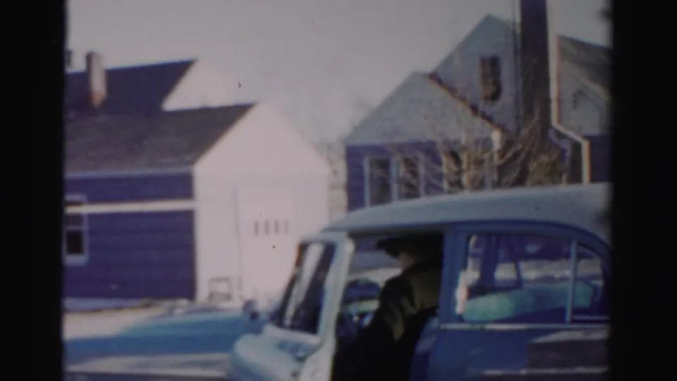 The blue car is prominent in the frame while the man is partly visible near the door on the snowy Albany street.