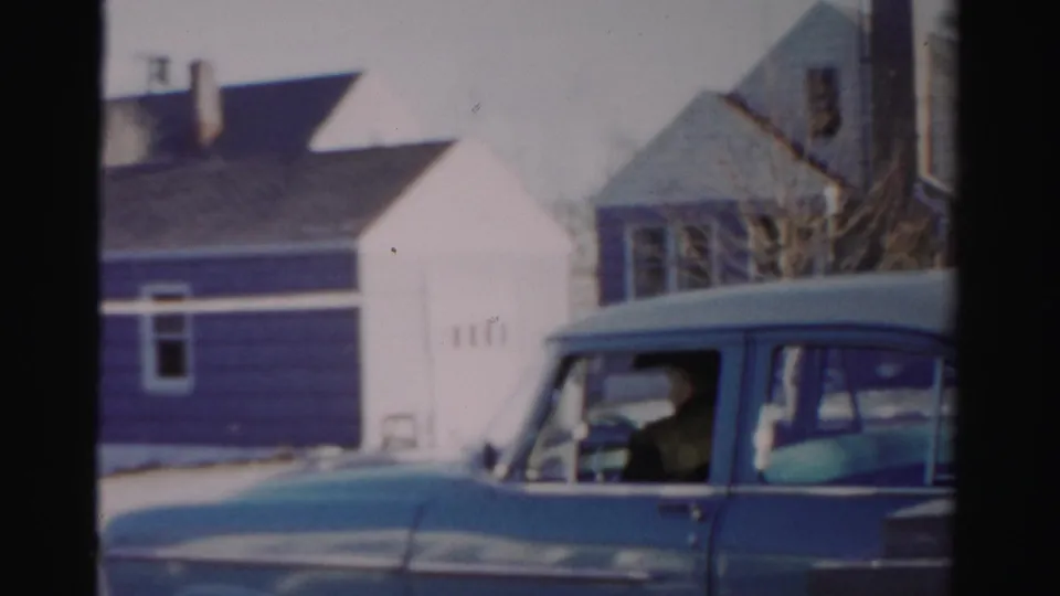The blue sedan fills the lower frame as the adult driver sits ready at the wheel on a cold-looking Albany street.