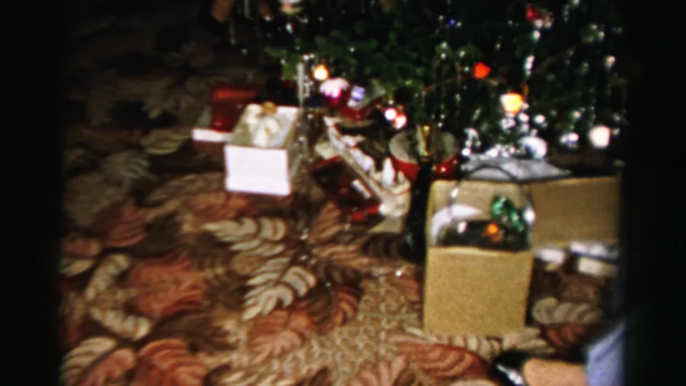 The lower half of the Christmas tree shows presents, boxes, tinsel, and a child partly visible in the private Albany living room.