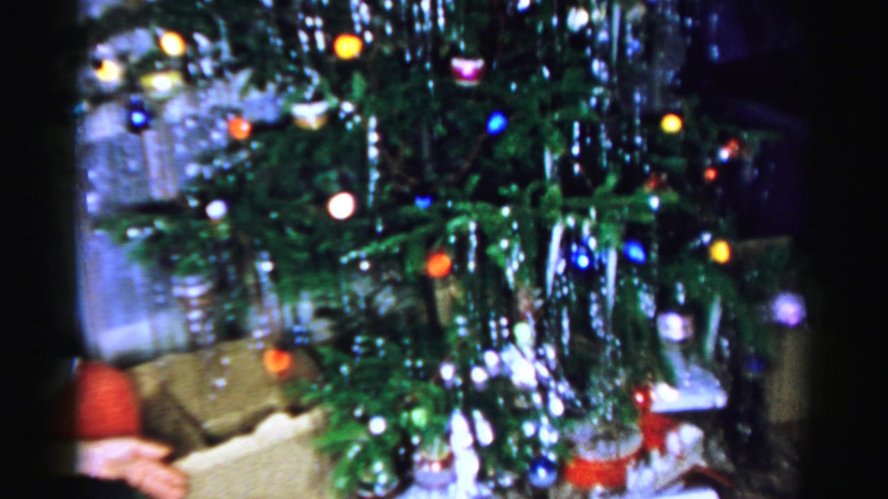 Decorated Christmas tree with lights, tinsel, and gifts below.