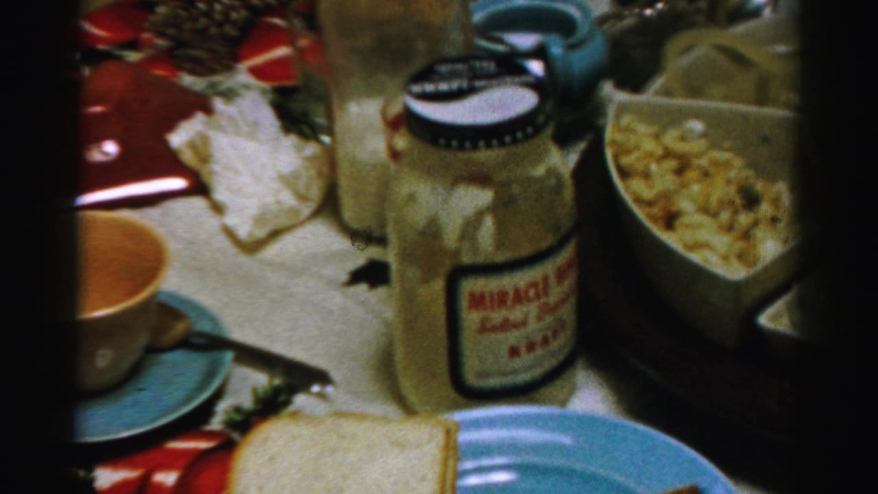 1956 Albany holiday table detail with a Miracle Whip jar, cup and saucer, bread, salad, pinecones, and red decorations.