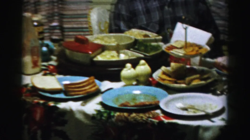 A 1956 Albany home table is crowded with serving bowls, plates with leftovers, toast or crackers, and a tiered tray.