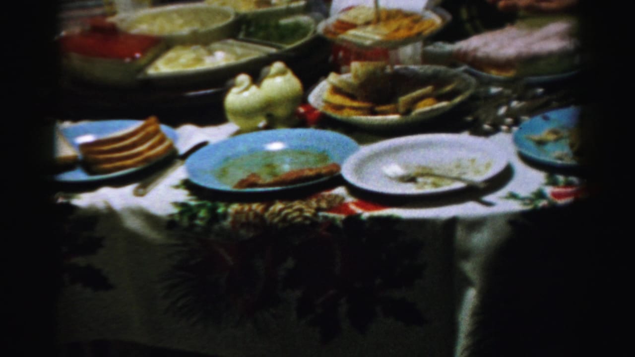 Festive table setting with serving bowls, plates, bread, cake, and holiday greenery.