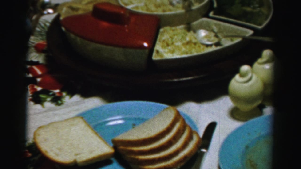 Close view of sliced bread, blue plates, ceramic shakers, and covered serving dishes.