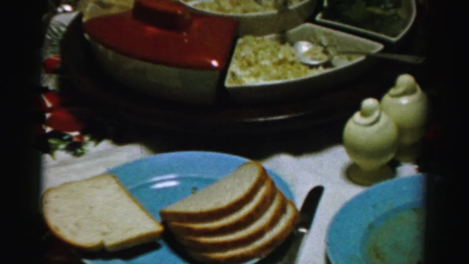 1956 Albany holiday table detail showing bread, blue plates, white ceramic shakers, and a red-lidded casserole.