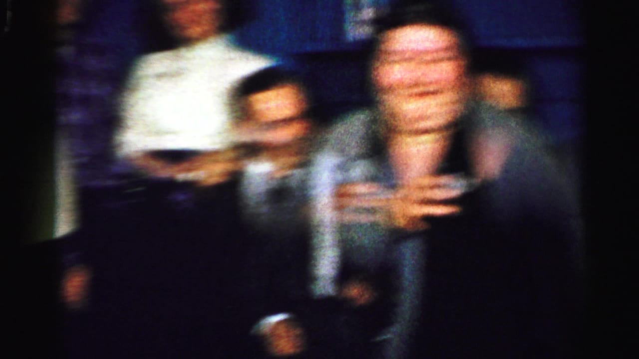 Blurred adults seated indoors during a dimly lit party.