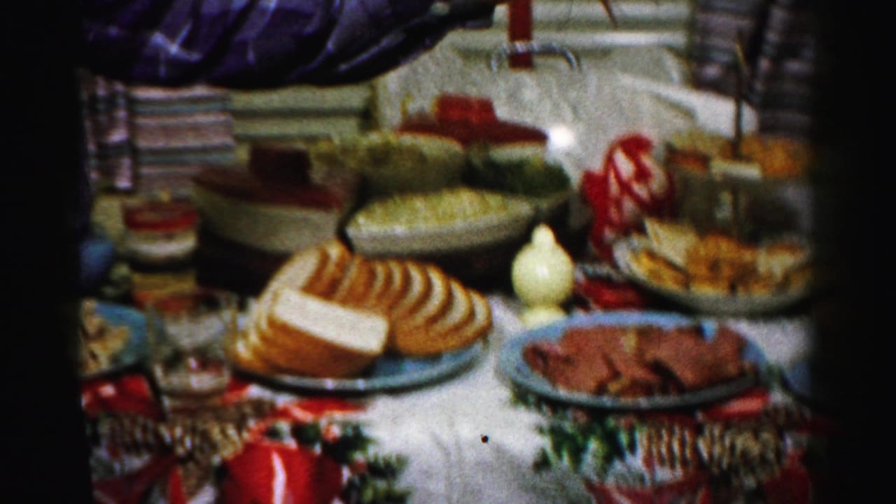Albany, New York home-movie frame showing a 1950s Thanksgiving table with bread, meat, bowls, and festive table covering.