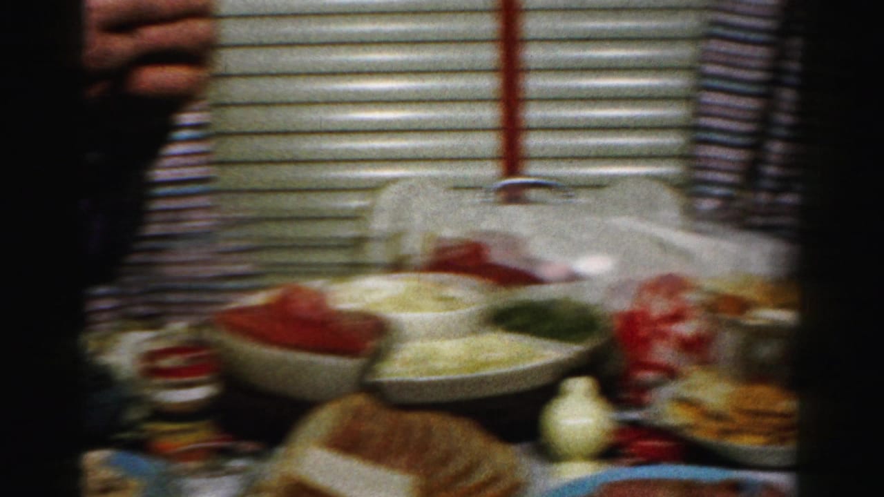 Handheld 8mm frame of a Thanksgiving food spread in a private Albany home, with bowls, bread, and striped curtains visible.