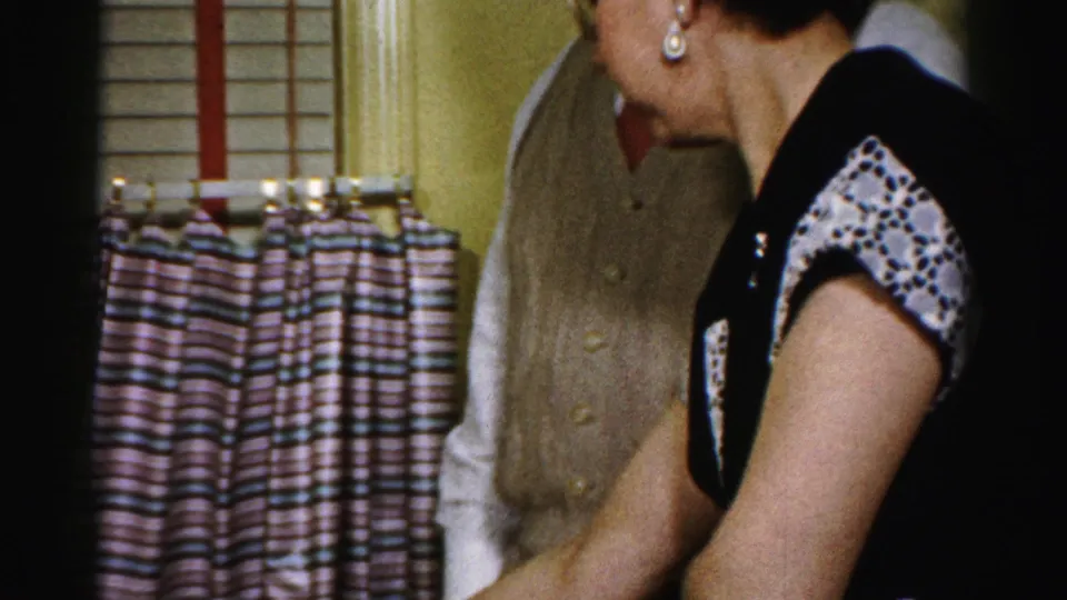 Adult woman in a patterned dress stands beside the Thanksgiving table in a private Albany home interior.
