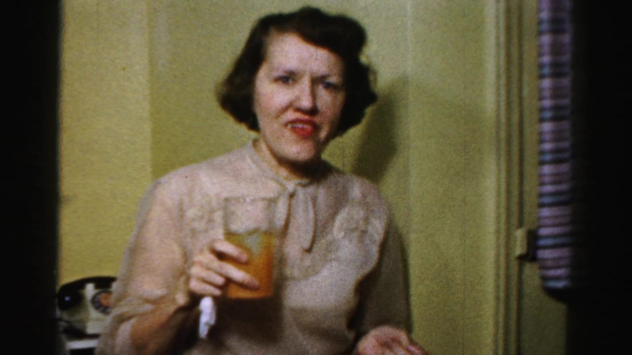 Adult woman in dressy 1950s attire holds a drink in a private Albany home interior.