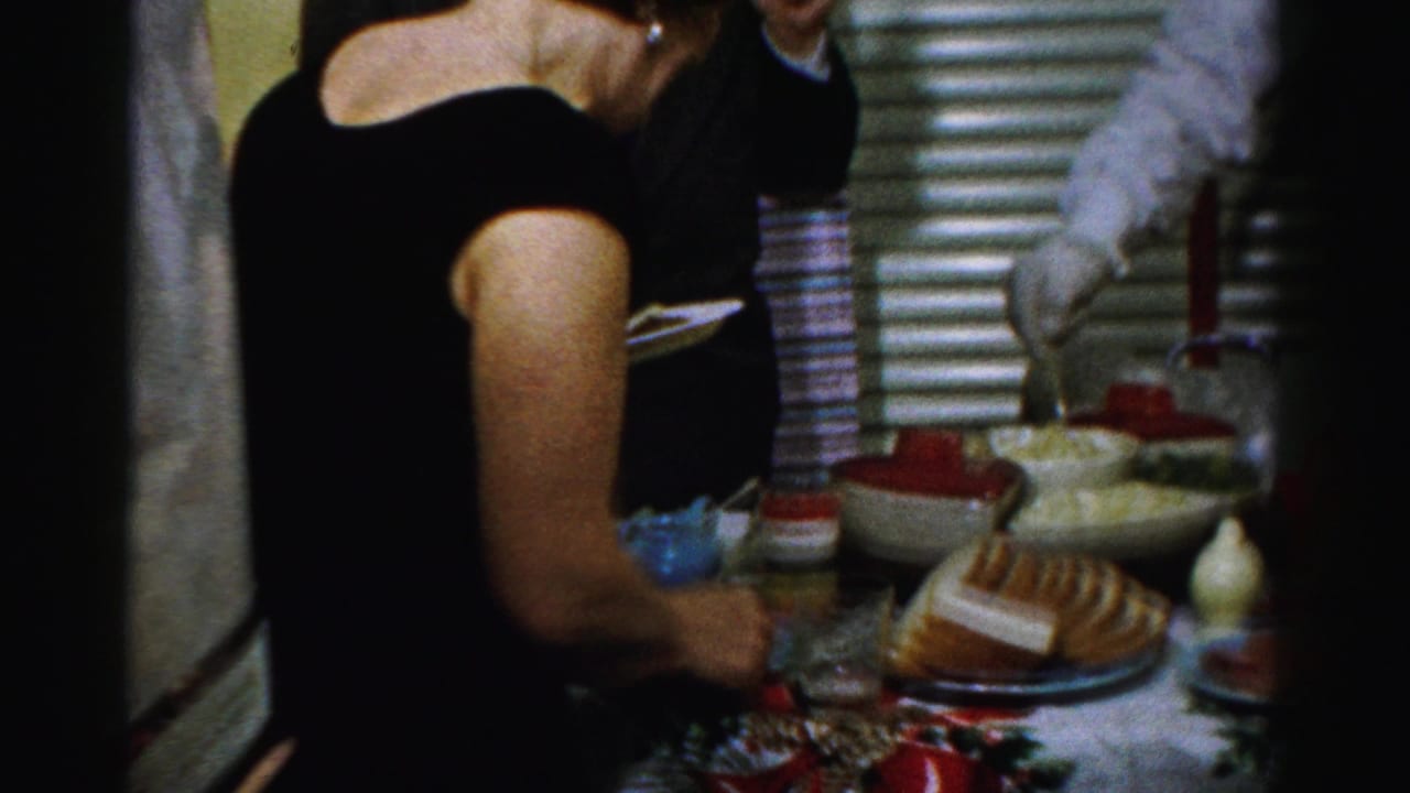 Guest in a black dress serves food from a crowded buffet table.