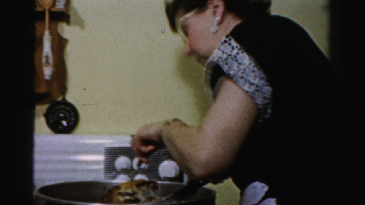 Woman cutting or stirring food in a pan on a white stove.