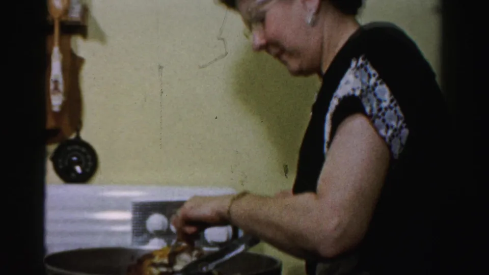 A side view shows the woman focused on the pan, with stove controls and a wall-mounted kitchen item visible behind her.