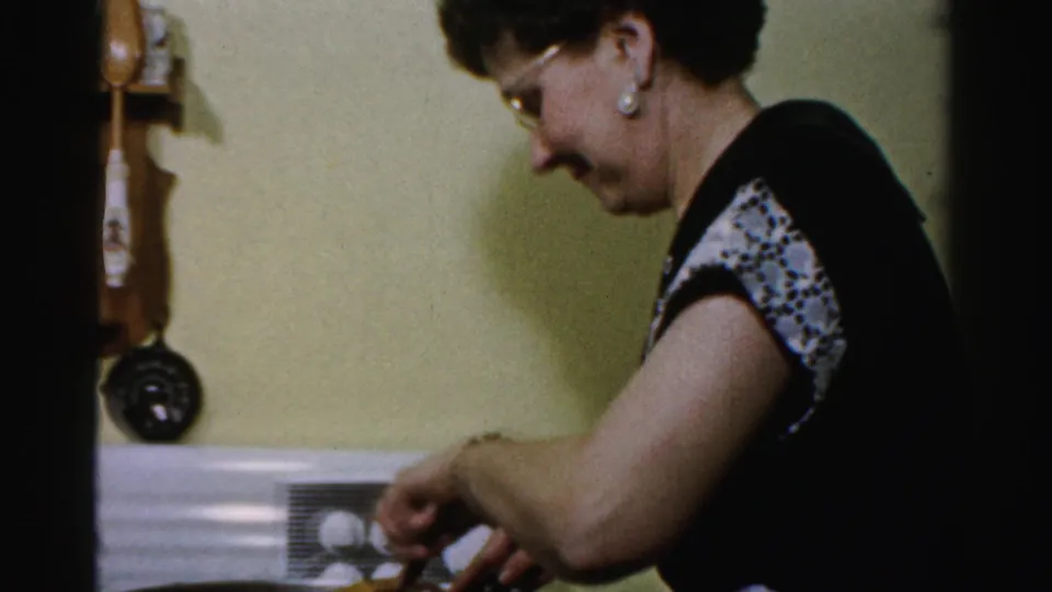 The final frame shows the woman smiling slightly as she continues using utensils over the pan in the private kitchen.