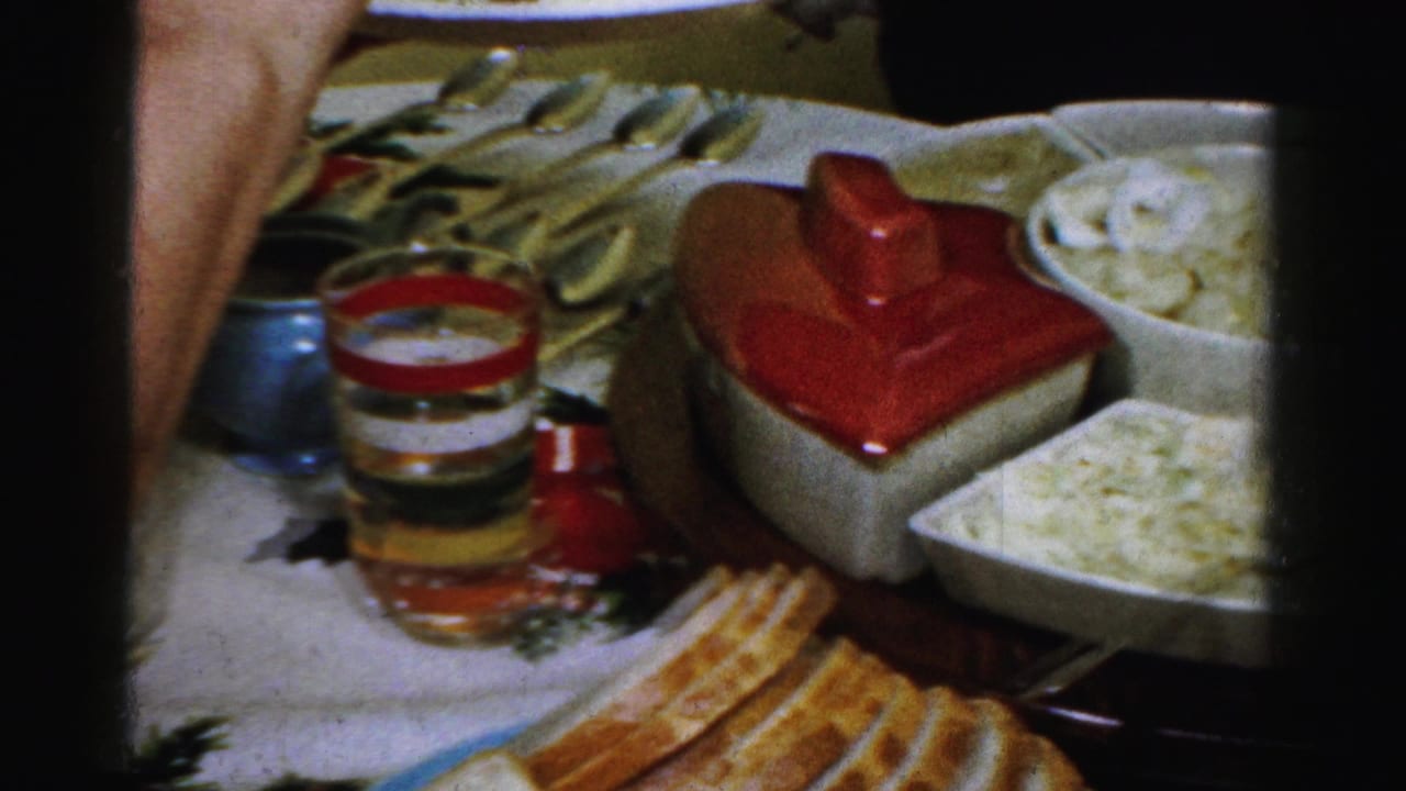 Table with serving dishes, food, utensils, and a red-lidded dish.