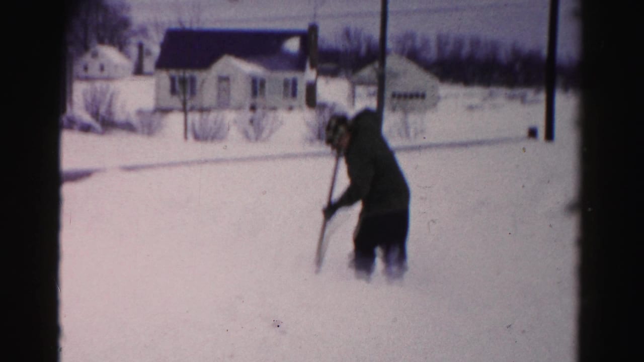 Man shoveling snow in a suburban yard, likely Albany, New York area, circa mid-1950s; wide snow coverage suggests a heavy storm.