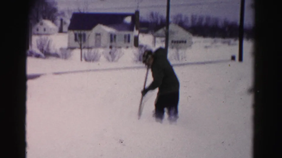 Man shoveling snow in a suburban yard, likely Albany, New York area, circa mid-1950s; wide snow coverage suggests a heavy storm.