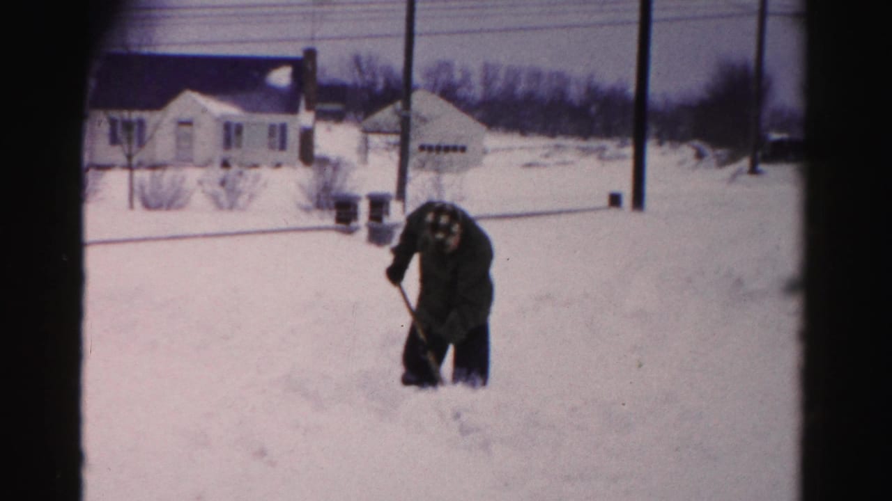 Man pausing while shoveling snow in a residential yard, Albany, New York area, circa mid-1950s, 8mm color film.