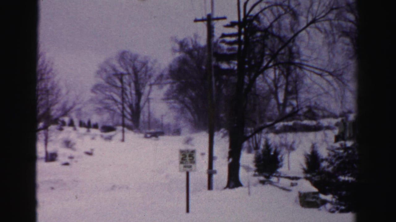 Snow-covered suburban street, possibly Albany, New York mid-1950s, with a 25 mph speed limit sign and utility poles framing a wide residential view.