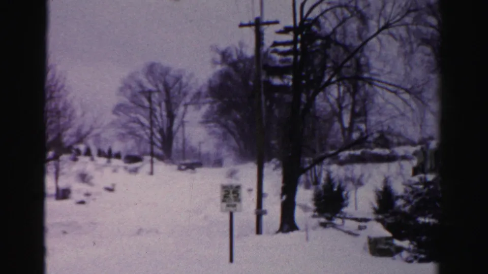 Snow-covered suburban street, possibly Albany, New York mid-1950s, with a 25 mph speed limit sign and utility poles framing a wide residential view.
