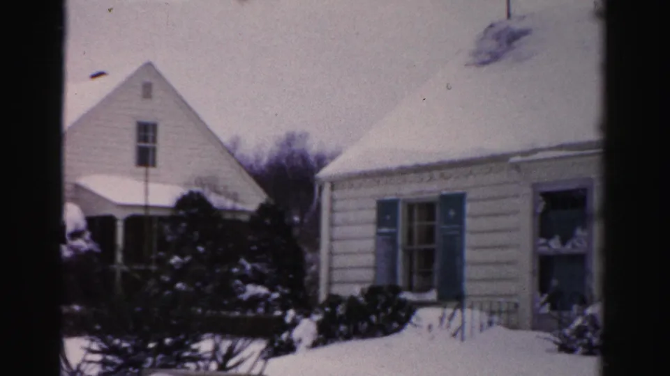 White clapboard house with blue-shuttered windows and deep snow on the roof; Albany, New York area, circa mid-1950s, 8mm color film.