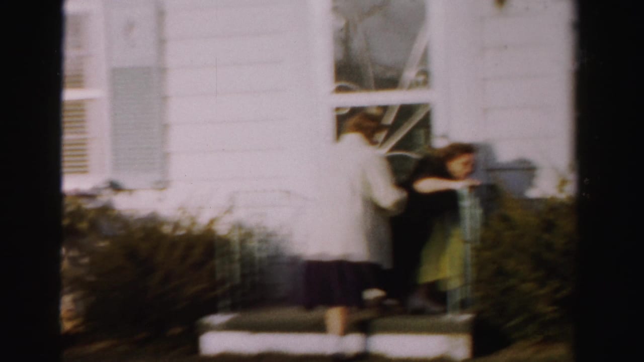 Two women on porch steps caught in motion, one showing a bright green skirt beneath a dark coat, blurred from movement.