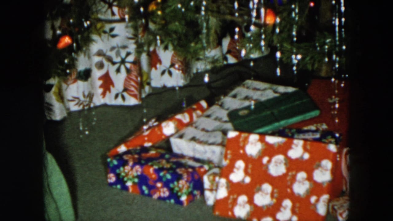 Wrapped Christmas presents under a decorated tree, featuring red Santa-print and blue floral packages with tinsel overhead.