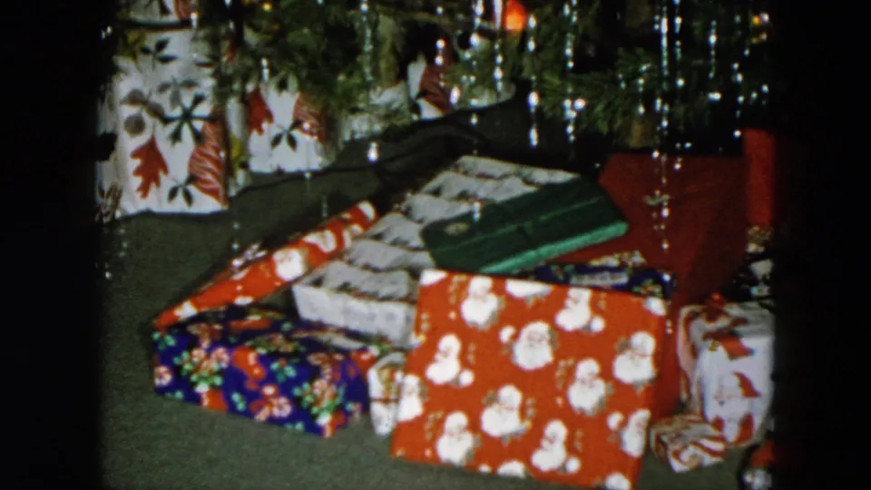 Christmas presents piled under a tinsel-decorated tree in an 8mm home movie from Hicksville, New York, circa 1956.