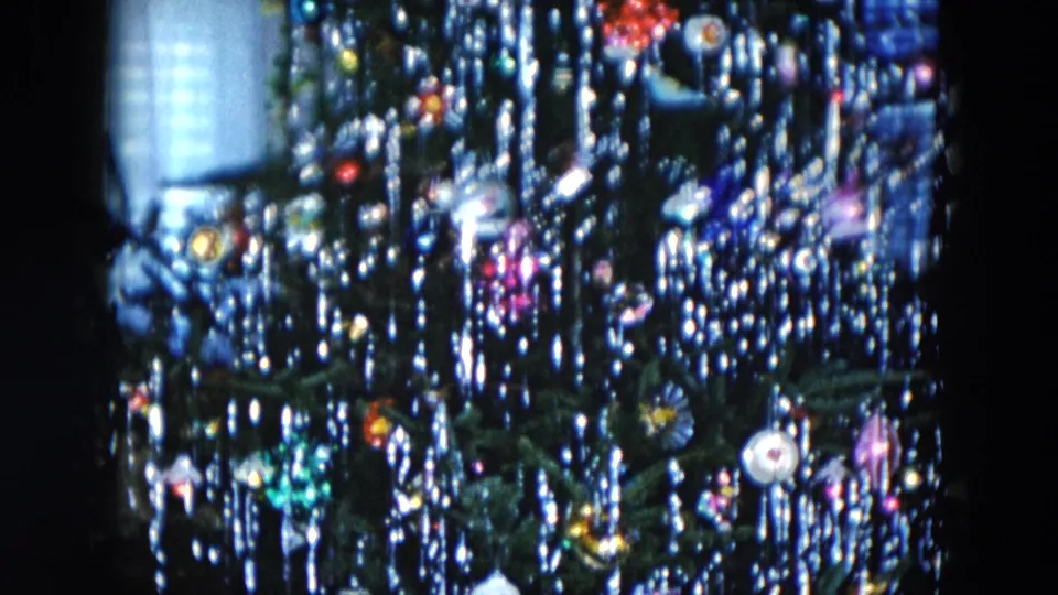 1956 Hicksville NY 8mm home movie: lit Christmas tree with glass ball ornaments and silver icicle tinsel against a near-black room interior