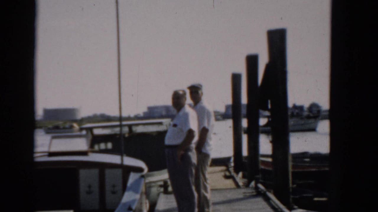 Two men in white shirts on a wooden dock near Catskill, New York, circa 1957, with waterfront structures visible in the background.