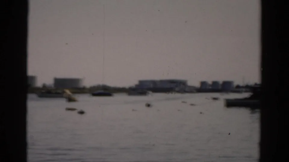 8mm frame circa 1957 from Catskill, NY waterfront panned to reveal low white buildings and small boats along the distant shoreline.