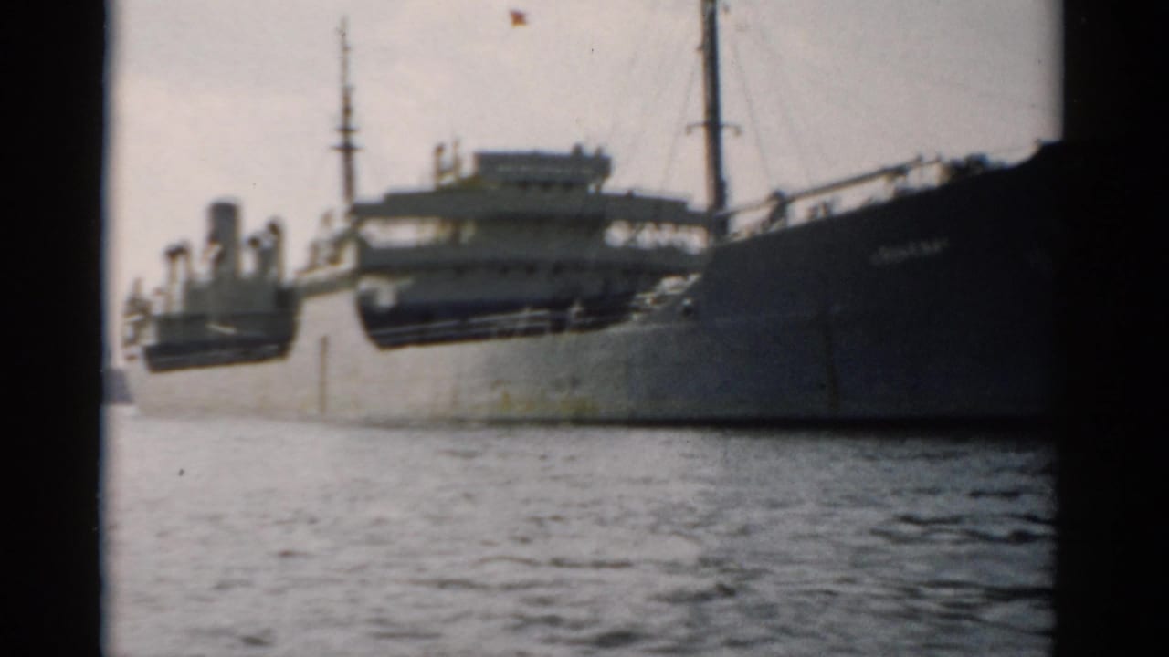 Large cargo ship alongside a concrete pier, filmed on 8mm circa 1957.