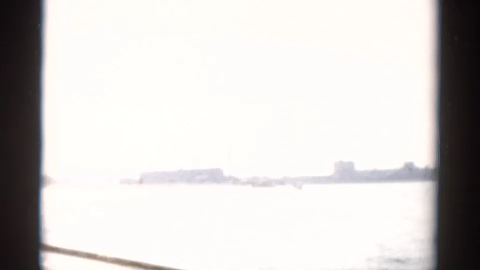 Overexposed 8mm frame from 1957 waterway sequence near Catskill, NY; bright glare obscures most detail, faint shoreline at horizon.
