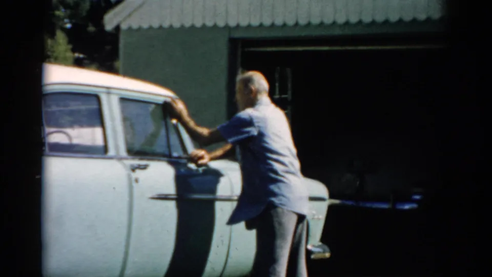 Man hand-wiping the driver's door of a pale blue mid-1950s sedan, circa 1957, Catskill area, New York.