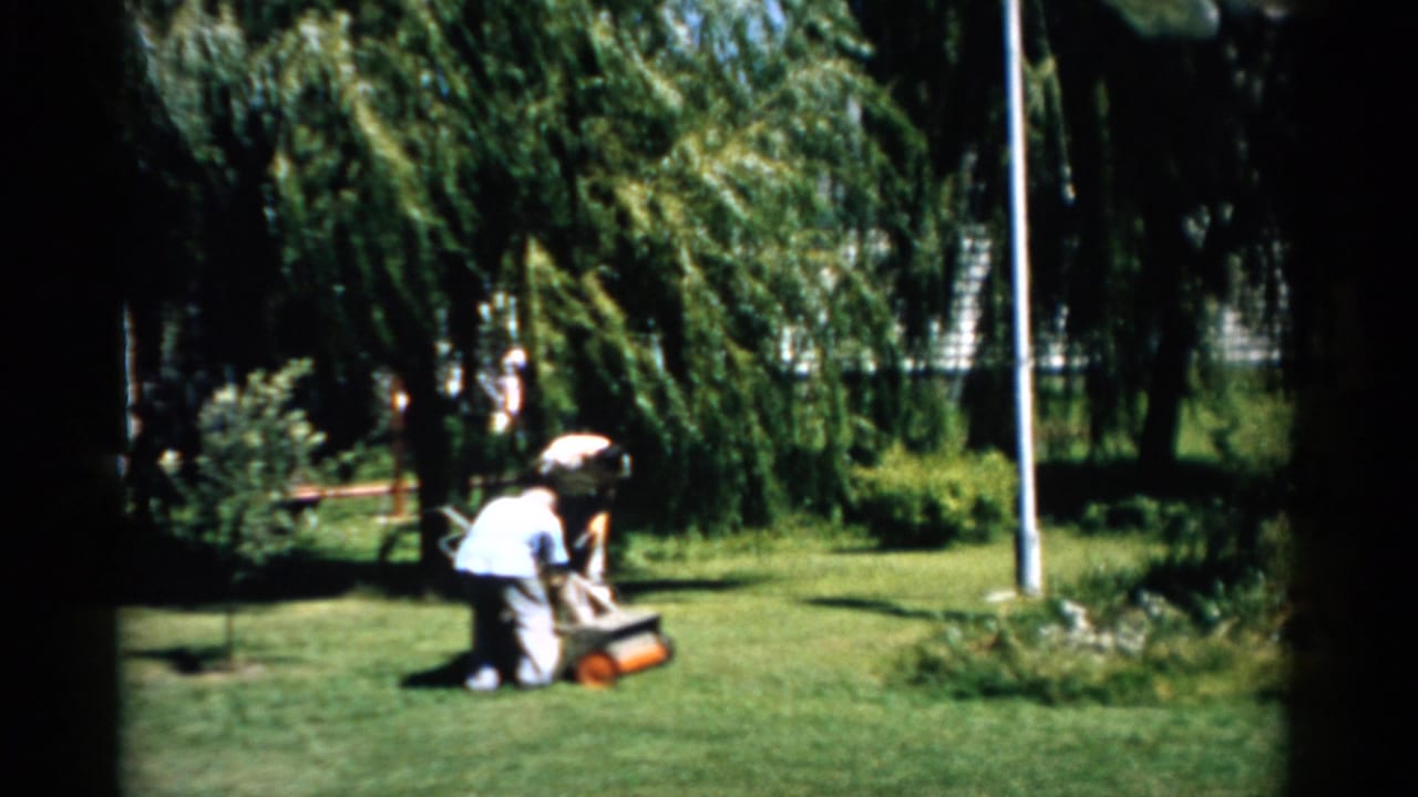Man and woman operating a reel lawn mower in a residential garden yard in Catskill, New York, circa 1957.