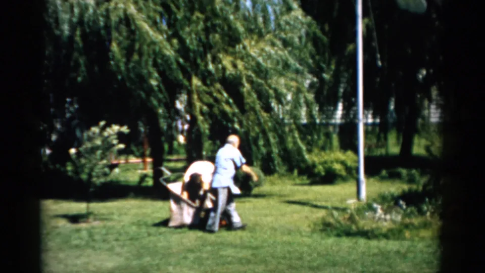 Man and woman adjusting positions near a reel mower in a residential yard, Catskill, New York, circa 1957.