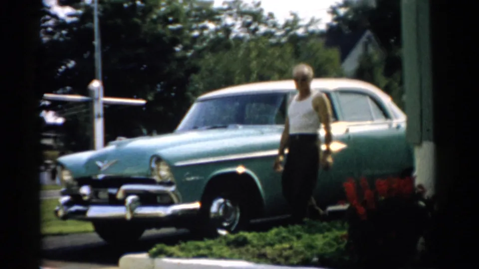 Man posing beside a two-tone teal mid-1950s American sedan on a residential street, Catskill, New York area, circa 1957.