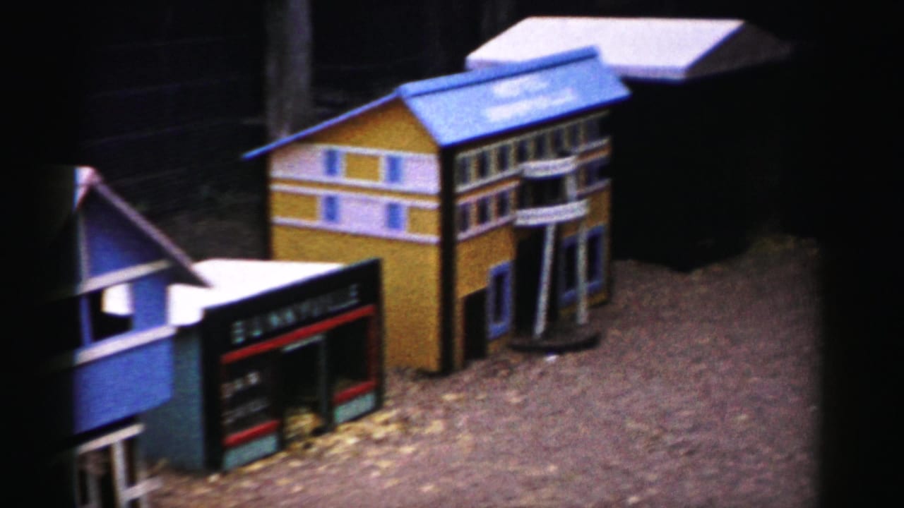 Hand-painted miniature wooden buildings—yellow structure with blue roof, dark 'Bunnyville' storefront sign—set on bark mulch; possibly a 1950s Catskill, New York tourist attraction.